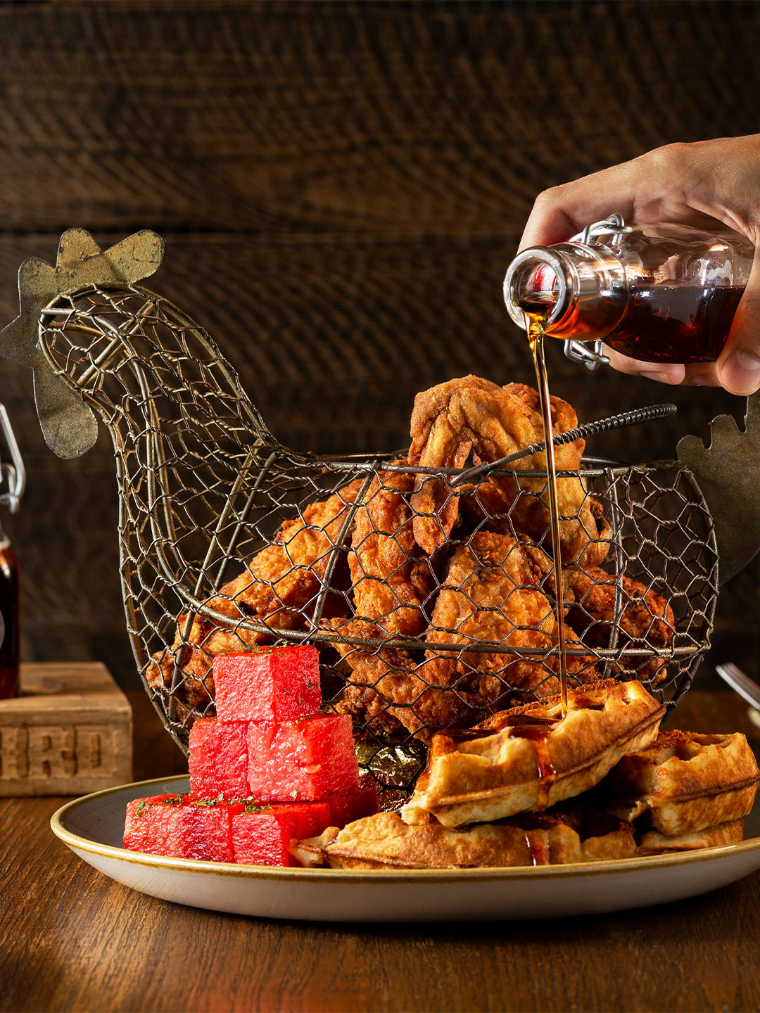 Person poring sauce over fried chicken at Yardbird, the best lunch place in Singapore