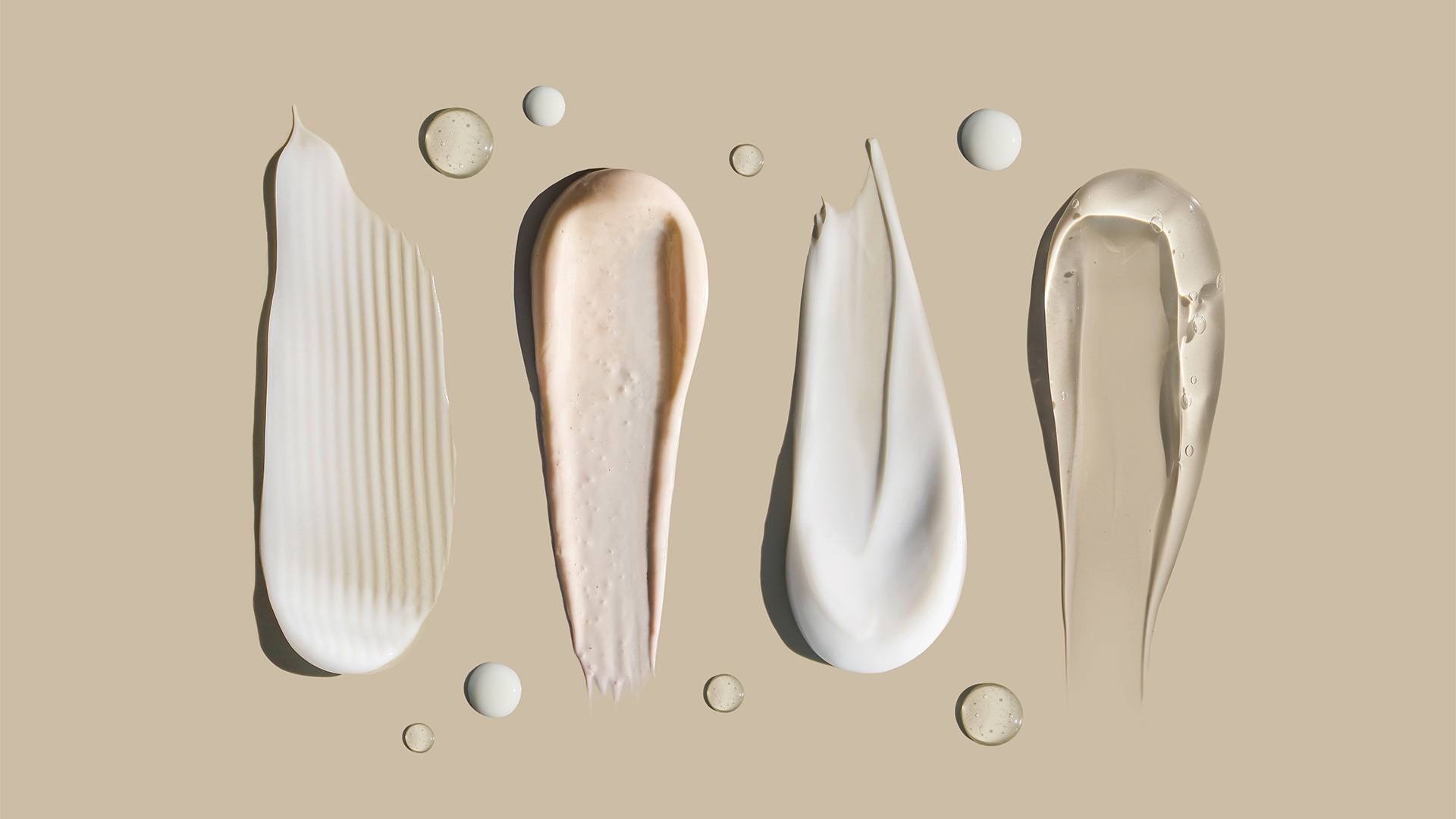Smears of skincare products with different consistency on a pastel background