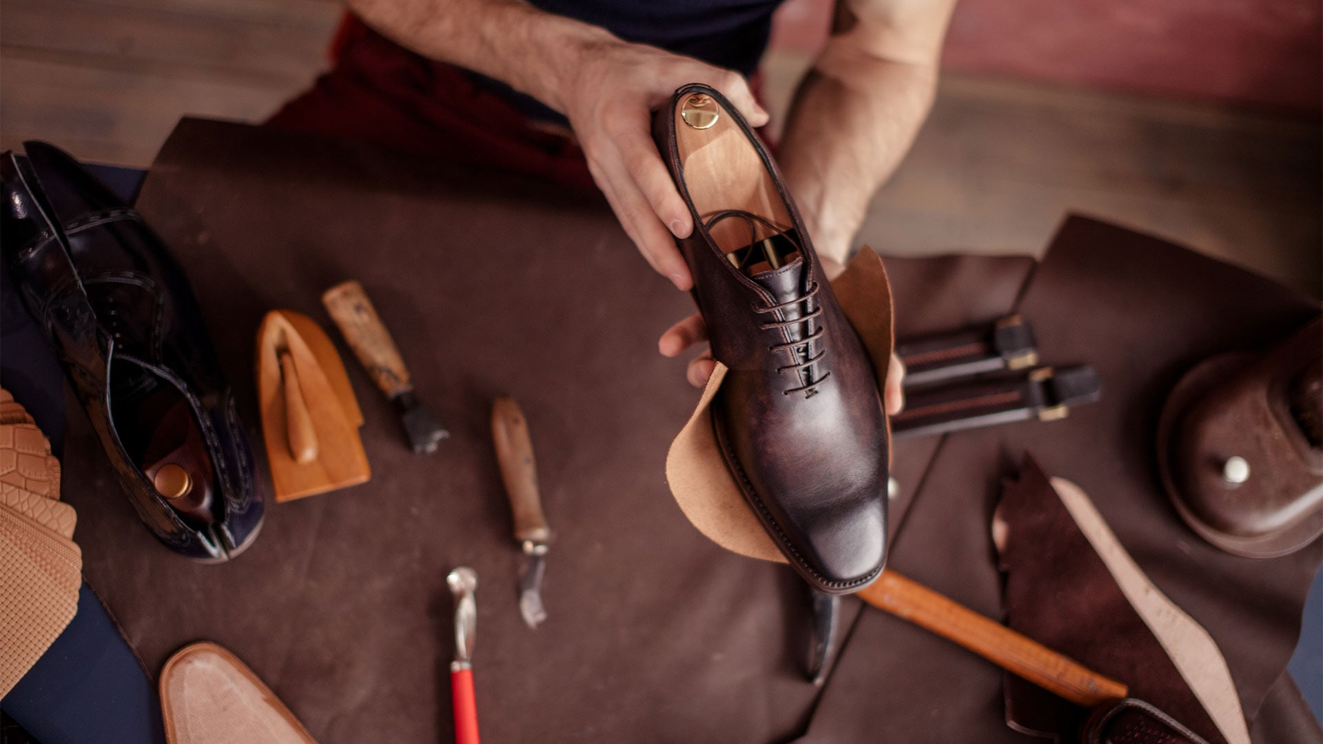 Man holding onto a men's leather shoe with excellent craftsmanship