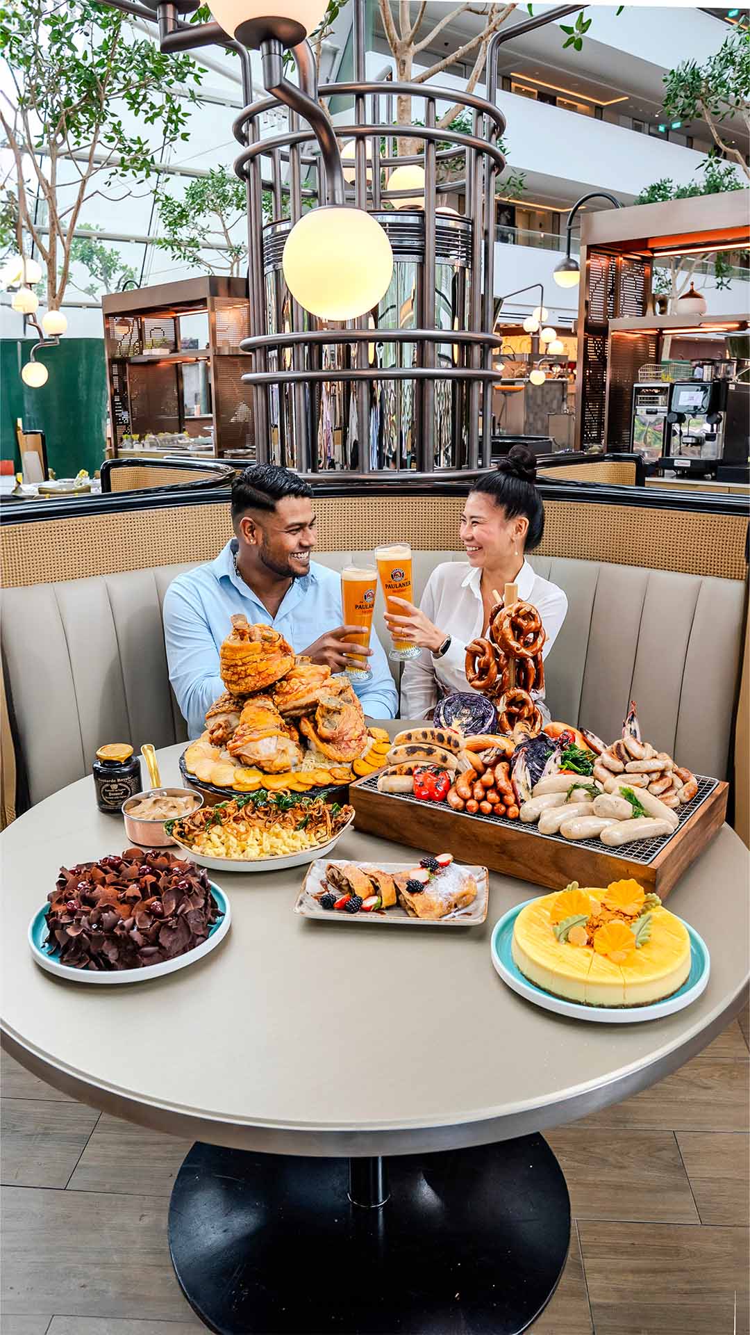 A man and woman with a spread of Bavarian dishes to celebrate Oktoberfest 2024 in Singapore