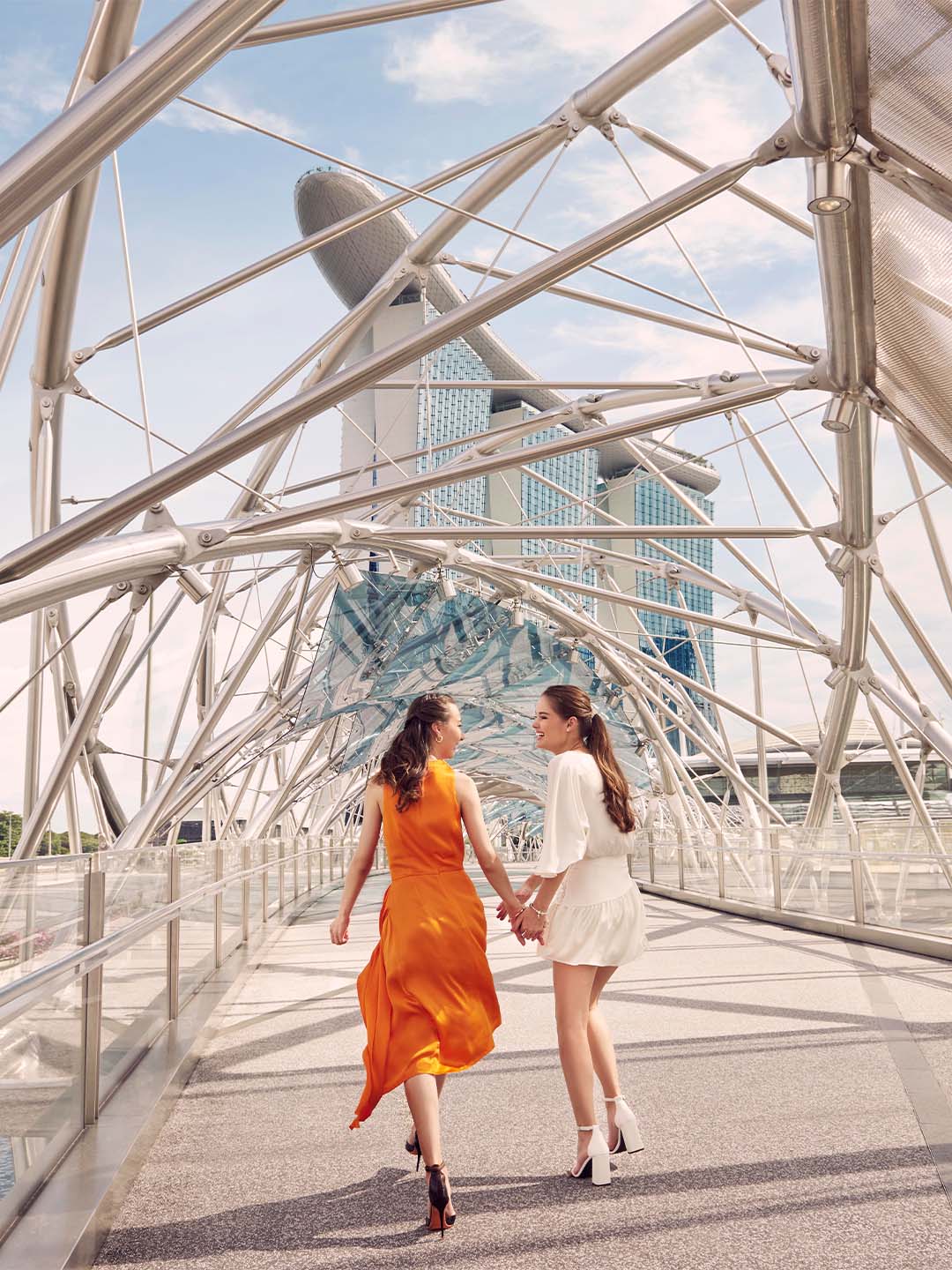 Friends walking down the Helix Bridge to Marina Bay Sands